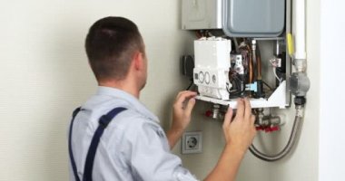 Tesisatçı konut ısıtma sorununu çözmeye çalışıyor. Gaz kazanı tamiri