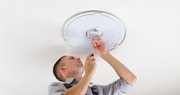 Young Man Electrician Fixing Chandelier Screws Fixing Screw Base Lamp — Stock Video