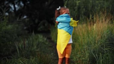 girl cheerfully runs through a wheat field with the flag of Ukraine. High quality FullHD footage