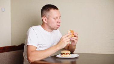 man eating burger at home. High quality FullHD footage