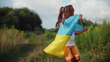 girl cheerfully runs through a wheat field with the flag of Ukraine. High quality FullHD footage