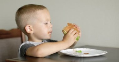 Little boy in fast food cafe eats burger. little kid eating burger. Hungry child in fast food cafe. 