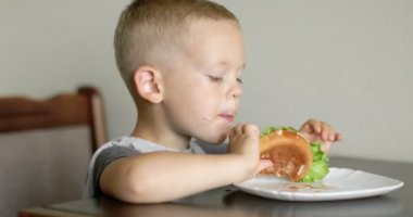 Little boy in fast food cafe eats burger. little kid eating burger. Hungry child in fast food cafe. 