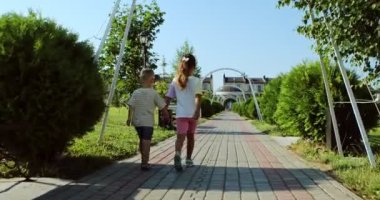 brother and sister walking in the park holding hands. High quality 4k footage
