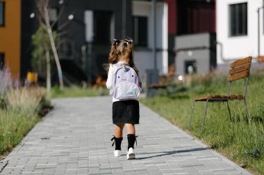 a little girl goes to school through the park along the path. distance education concept. 
