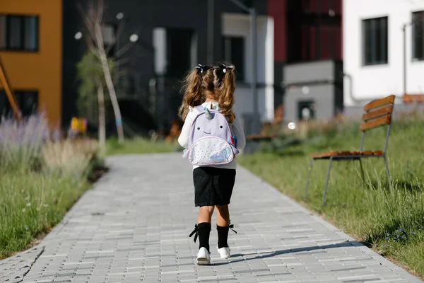 a little girl goes to school through the park along the path. distance education concept.