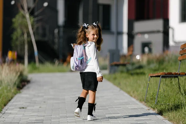 a little girl goes to school through the park along the path. distance education concept.