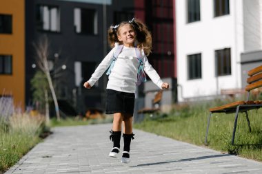 a little girl goes to school through the park along the path. distance education concept. 
