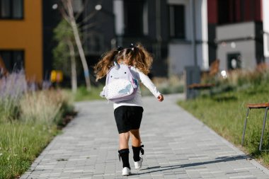a little girl goes to school through the park along the path. distance education concept. 
