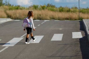 schoolgirl crosses the road at a pedestrian crossing