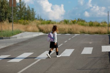 schoolgirl crosses the road at a pedestrian crossing