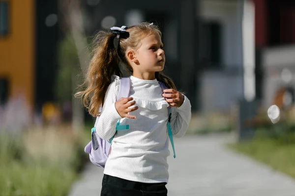 a little girl goes to school through the park along the path. distance education concept.