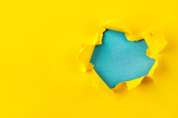 Желтая и синяя дыра в бумаге с разорванными сторонами. Концепция войны на Украине