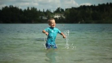 Çocuklar güneşli bir yaz gününde kumların üzerinde nehir kıyısında oynarlar..