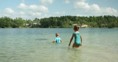 Çocuklar güneşli bir yaz gününde kumların üzerinde nehir kıyısında oynarlar..