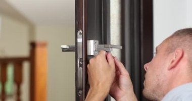 man repairing the doorknob. closeup of workers hands installing new door locker. High quality 4k footage