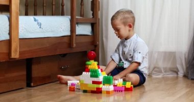 Funny baby boy with educational toy blocks. Children play at day care or preschool. Mess in kids room. Toddlers build a tower in kindergarten. Child playing with colorful toys.