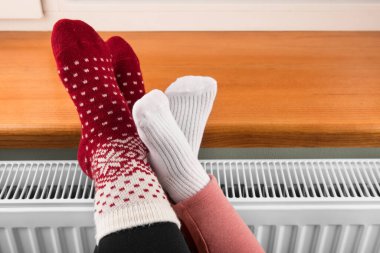 Küçük bir kız kaloriferde ellerini ve ayaklarını ısıtıyor.