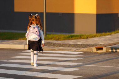 schoolgirl crosses the road at a pedestrian crossing.