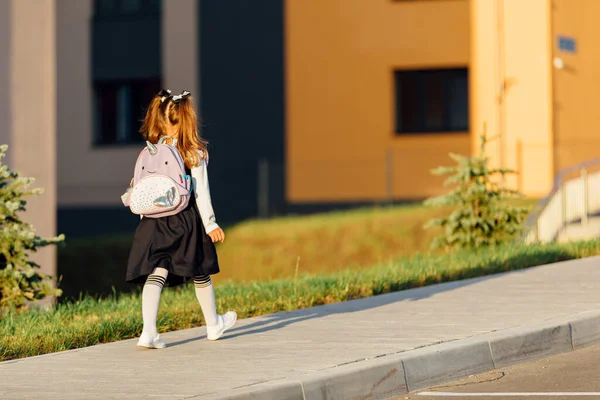 a little girl goes to school through the park along the path. distance education concept. school girl returning home from school