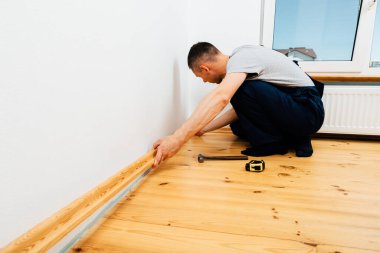 Onarım yapmak için. Yeni bir etek panosu kuruyorum. Bir adam odada tamirat yapar..