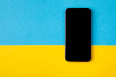 Ukrayna bayrağının arka planında boş ekran cep telefonu.
