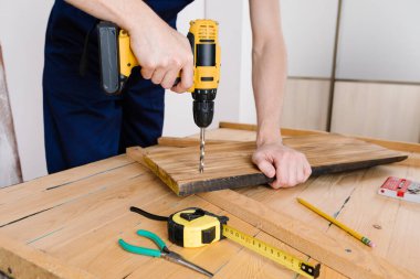 Mavi üniformalı tamirci otomatik tornavidayla çalışıyor. Ev yenileme konsepti.