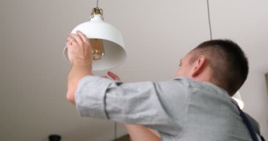 Elektrikçi lambaya yeni bir ampul yerleştirir. Yüksek kalite 4k görüntü