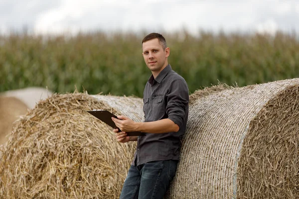 young agronomist holds a paper chart in his hands and analyzes the corn crop.