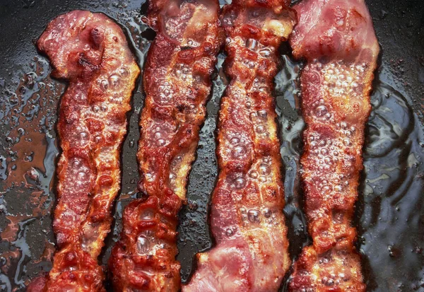 Bacon slice being cooked in frying pan — Stock Photo, Image