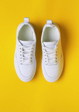 Sarı arka planda beyaz spor ayakkabı