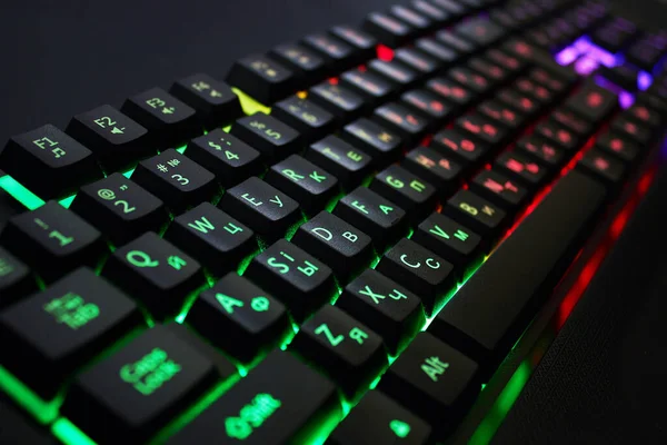 Gaming keyboard with RGB light, on black background, close up