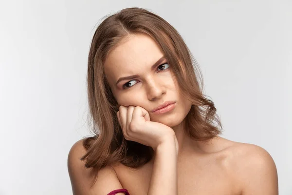 Schöne nette brünette Mädchen mit einem unzufriedenen Gesicht. Studioporträt. — Stockfoto