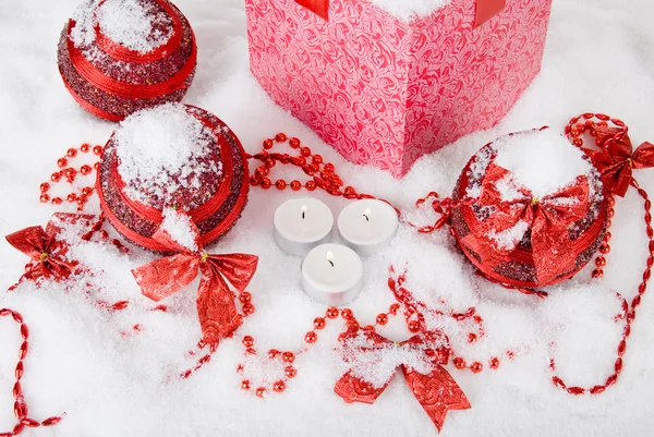 Caixa de presente de Natal na neve com bolas vermelhas e velas — Fotografia de Stock