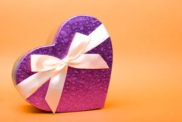 Caja de regalo de corazón único con cinta sobre fondo amarillo . — Foto de Stock