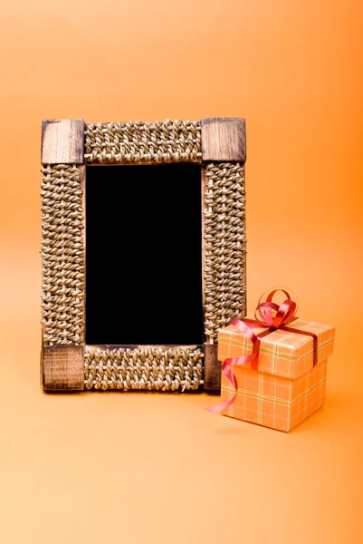 Foto frame en gift box met lint op oranje achtergrond. — Stockfoto