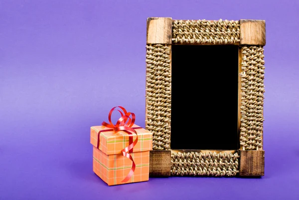 Marco de fotos de madera y caja de regalo naranja con cinta roja en azul b — Foto de Stock