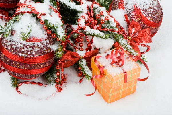 Árvore de Natal na neve com bolas vermelhas e caixa de presente — Fotografia de Stock