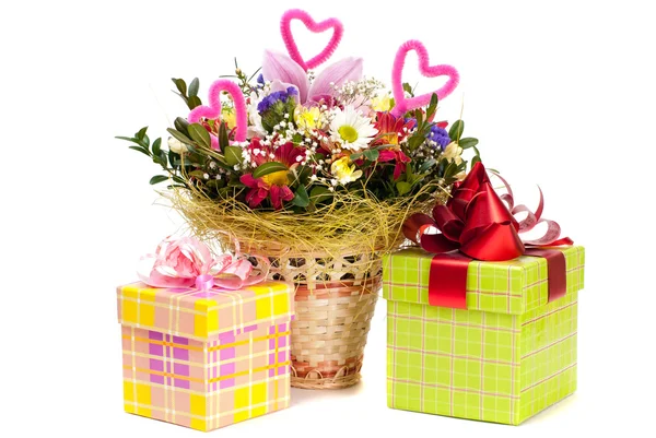 Beautiful bouquet in the basket and present boxes on a white bac — Stock Photo, Image