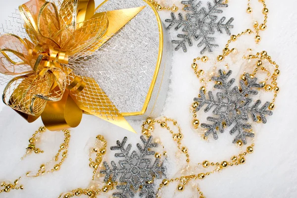 Confezione regalo natalizia cuore argento con nastro dorato sulla neve su un Fotografia Stock