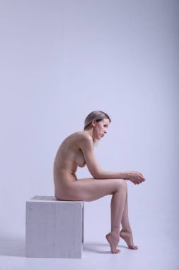 Gri arka planda vücuduna uyduğunu gösteren güzel, çarpıcı, çıplak bir kadın.. 