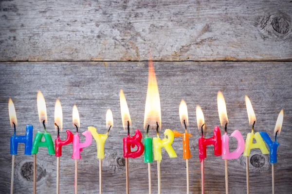 Birthday kaarsen branden tegen houten achtergrond — Stockfoto