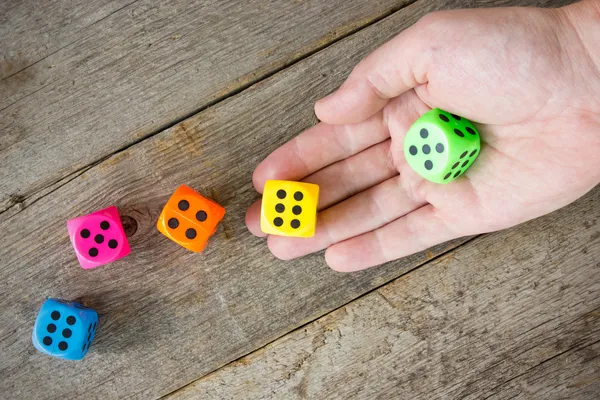 Hand throwing colorful dice — Stock Photo, Image