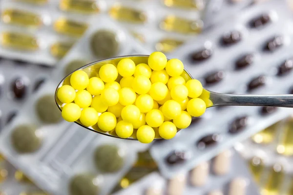 Spoon with yellow pills — Stock Photo, Image