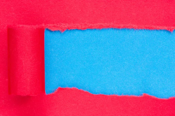 Red paper torn to reveal blue panel — Stock Photo, Image