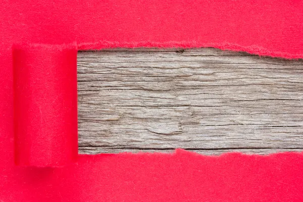 Red paper torn to reveal wooden panel