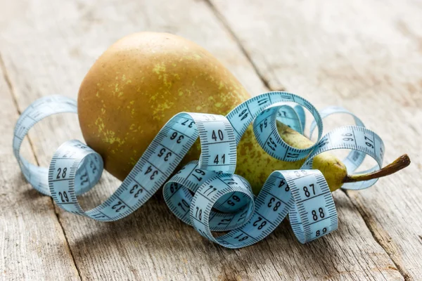 Pear and measuring tape on the floor Royalty Free Stock Images