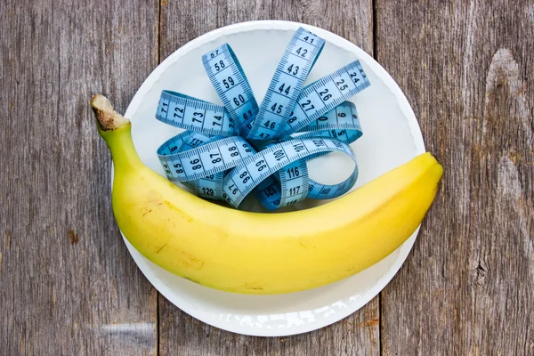 Cinta medición y plátano en un plato —  Fotos de Stock