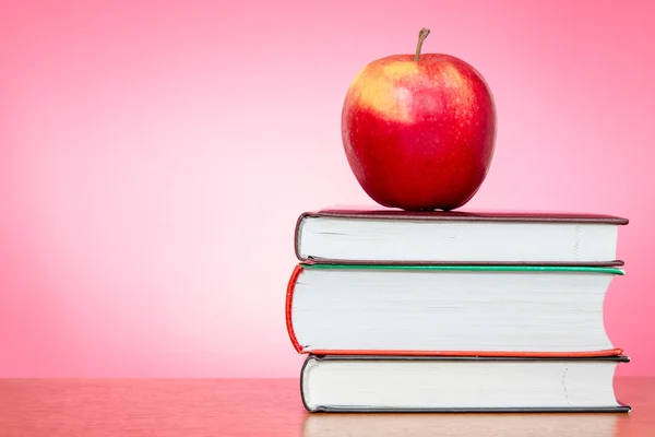 Knihy a apple s růžovým pozadím — Stock fotografie