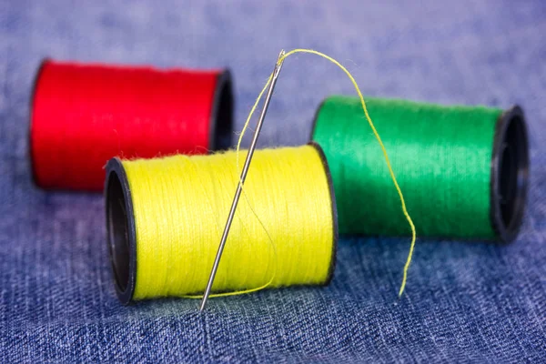 De nld met spoelkokers op jeans materiaal — Stockfoto